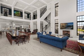 Ein großzügiger Innenraum mit Essbereich, Wohnzimmer mit blauem Sofa, Treppe und Küche.