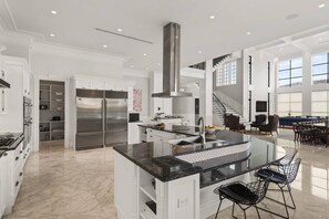 Cozinha espaçosa com ilha central, eletrodomésticos de aço inoxidável e uma janela grande que oferece iluminação natural.