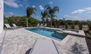 A rectangular swimming pool with a hot tub, surrounded by a paved deck and lounge chairs. - 8BR Encore Villa Retro Game Room & Pool (Kissimmee)