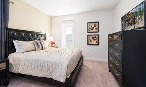 A bedroom with a large bed, a dresser, a nightstand, and a window. - 8BR Encore Villa Retro Game Room & Pool (Kissimmee)