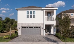 A two-story house with a garage, a balcony, and a well-maintained front yard. - 8BR Encore Villa Retro Game Room & Pool (Kissimmee)
