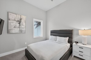 A bedroom with a bed, a nightstand, a lamp, and two wall art pieces. - 5BR Reunion Resort Condo With Elevator and Share Pools (Kissimmee)