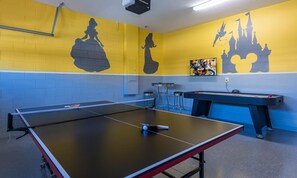 A ping pong table with a net, a pool table, and wall art including silhouettes of a castle and a castle with a Mickey Mouse. - 6BR Encore Villa With Game Room & Private Pool (Kissimmee)