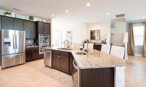 A modern kitchen with stainless steel appliances, dark cabinetry, and a granite countertop island. - Chic Property With Private Pool in Encore (Kissimmee)