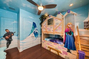 Ein Zimmer mit Etagenbett, Deckenventilator, Wandgemälde und einer Figurenstatue.