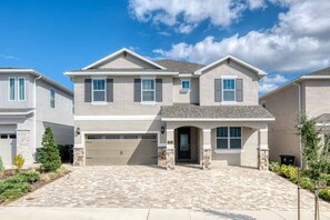 A two-story residential building with a garage, a front entrance, and a driveway. - Elegant Villa With Games Room at Encore (Kissimmee)