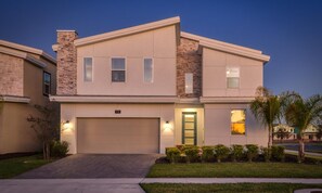 A two-story residential building with a garage, a stone accent wall, and a well-lit entrance. - 8BR Championsgate Theater, Arcade & Pool (Davenport)