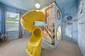A playroom with a slide, a bed, and a window with curtains. - Charming Estate With Themed Bedrooms at Encore (Kissimmee)