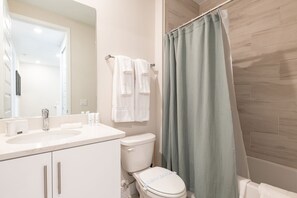 Une salle de bain avec un lavabo blanc, des toilettes et un rideau de douche.