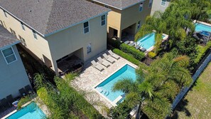 A residential building with a swimming pool, outdoor seating, and lush greenery. - 8BR Encore Villa Pool, Spa & Loft (Kissimmee)