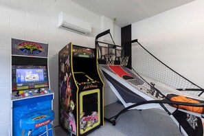 A multi-game arcade machine and a basketball hoop in a room with white walls and a concrete floor. - 8BR Encore Villa Pool, Spa & Loft (Kissimmee)