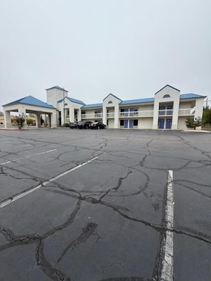 A building with multiple floors, a parking lot, and a blue-roofed entrance.
