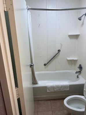 A bathroom with a bathtub, a toilet, and a shower area.