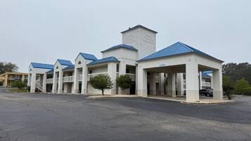 A hotel with a central tower, multiple wings, and a parking lot.