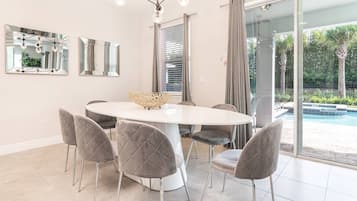 Un comedor moderno con una mesa redonda, seis sillas y dos espejos en la pared.