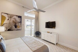 A modern hotel room with a large bed, a flat-screen TV, a white dresser, and a large abstract painting on the wall. - 6BR Reunion Mansion Circus Room & Karaoke (Kissimmee)