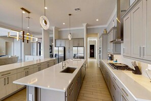 A modern kitchen with a central island, stainless steel appliances, and pendant lighting. - 6BR Reunion Mansion Circus Room & Karaoke (Kissimmee)