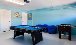 A pool table with balls, blue bean bag chairs, and a foosball table in a room with light blue walls and white doors. - 6BR Championsgate Villa Pool, Spa & Game Room (Davenport)