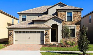 A two-story house with a stone facade, a tiled roof, and a garage. - 6BR Championsgate Villa Pool, Spa & Game Room (Davenport)
