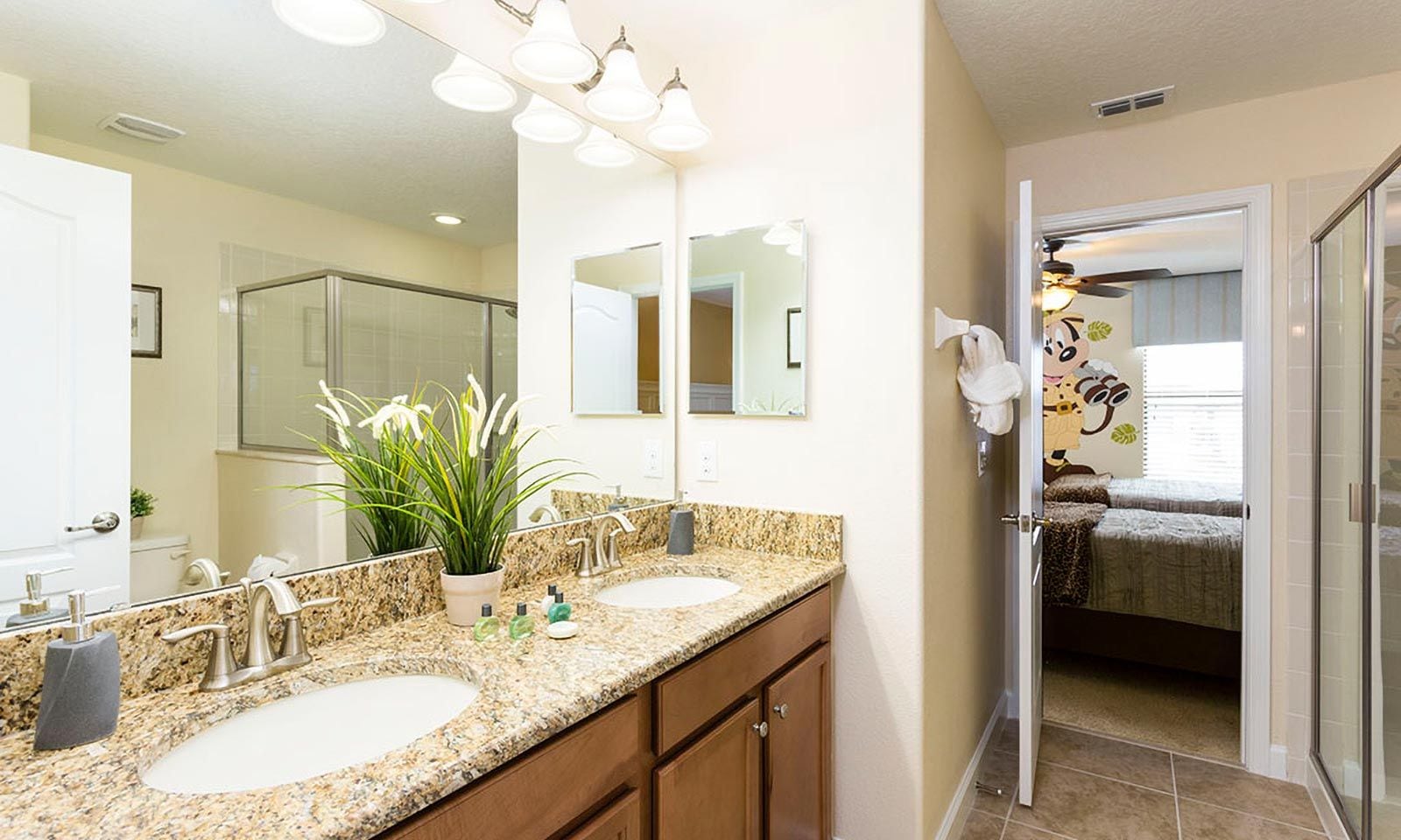 A bathroom with two sinks, a mirror, a potted plant, and a shower area.