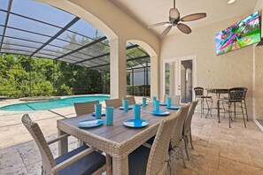 An outdoor patio with a pool, dining table, chairs, and a ceiling fan. - Deluxe Villa With Guest Suite at Reunion (Kissimmee)