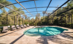 A covered outdoor swimming pool with lounge chairs and a pergola structure. - Deluxe Villa With Guest Suite at Reunion (Kissimmee)