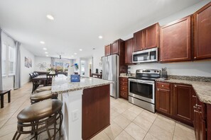 A modern kitchen with wooden cabinets, stainless steel appliances, and a granite countertop. - 8BR pet Friendly Home With Private Pool at Encore (Kissimmee)