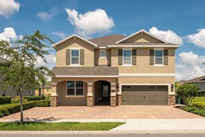 A two-story house with a garage, a front entrance, and a driveway. - Encore 8BR Home, Pool & Spa, 10 Min to Disney (Kissimmee)