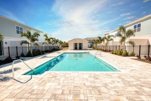 Piscina rectangular con una escalera metálica, rodeada por un patio empedrado.
