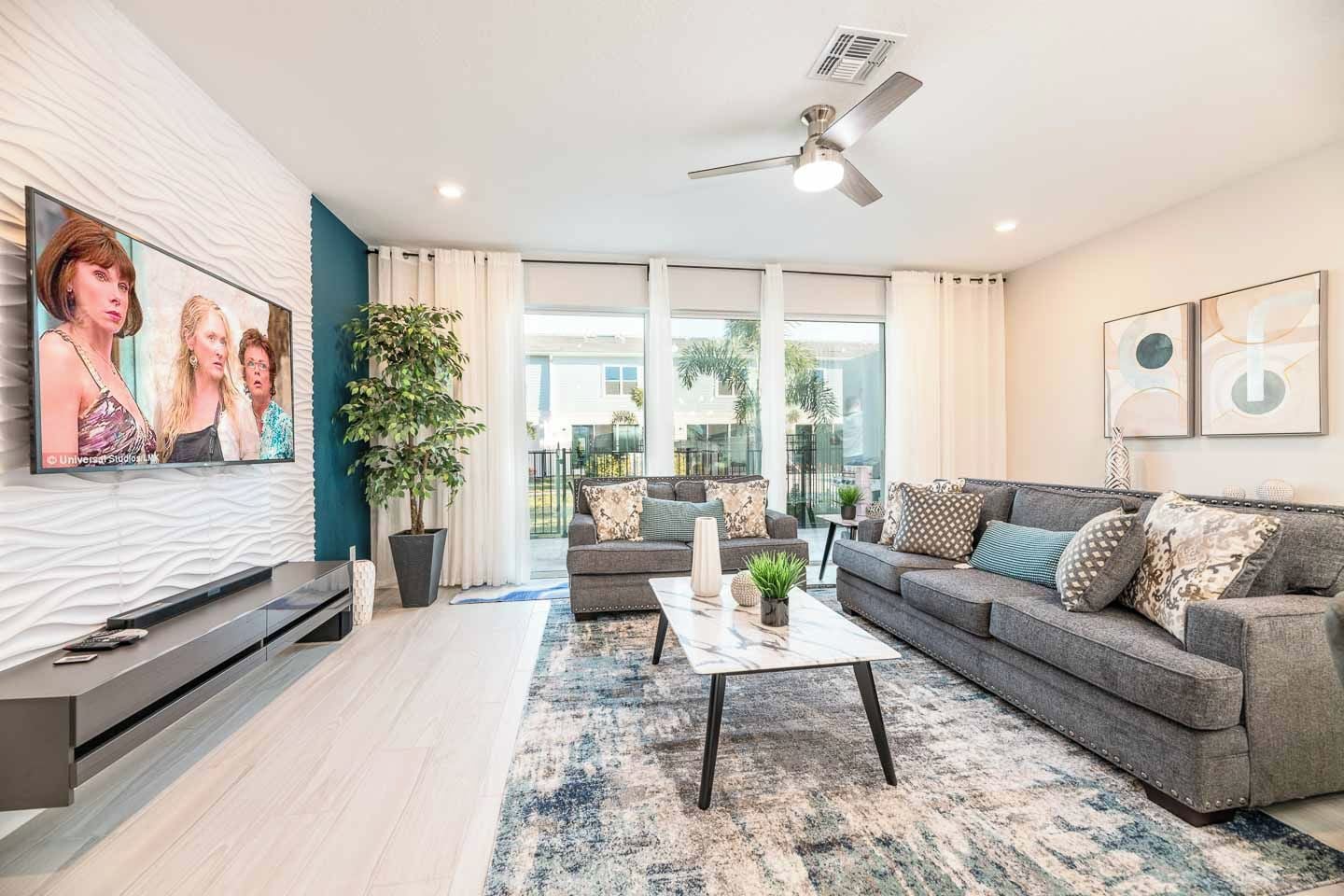 A modern living room with a grey sofa, a coffee table, and a TV on a wall.