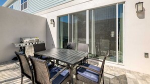 Eine Terrasss mit Grill, Tisch und Stühlen.