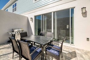 Een terras buiten met een barbecue, tafel en stoelen.
