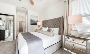 A hotel room with a large bed, a bedside table, a mirror, and a window with blinds. - Encore 8BR Villa, Putting Green, Near Disney (Kissimmee)