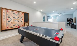 Ein Zimmer mit einem Kicker, einem großen Scrabble-Spiel und einem Fenster mit Blick auf eine Stadtlandschaft.
