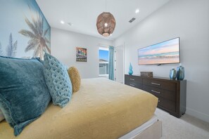 A bedroom with a bed, a dresser, a television, and a door leading to a balcony. - 8BR Estate Reunion Water Park & Resort Pools (Kissimmee)