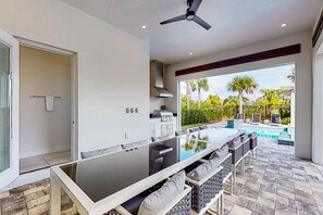 A modern kitchen with a central island, a ceiling fan, and a view of a swimming pool. - 8BR Estate Reunion Water Park & Resort Pools (Kissimmee)