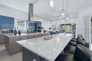 A modern kitchen with a large island, built-in appliances, and pendant lighting. - 8BR Estate Reunion Water Park & Resort Pools (Kissimmee)