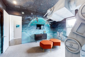 Ein Zimmer mit Wandgemälde eines Sternenhimmels, großem Fenster und modernem Design.