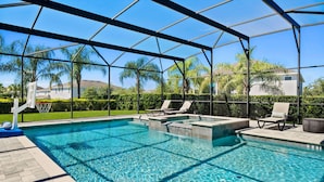 A clear swimming pool with a sunshade structure, lounge chairs, and a basketball hoop. - 8BR Vacation Home With Screened Pool Area (Kissimmee)