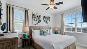 A bedroom with a bed, two nightstands, a ceiling fan, and artwork on the walls. - 8BR Vacation Home With Screened Pool Area (Kissimmee)