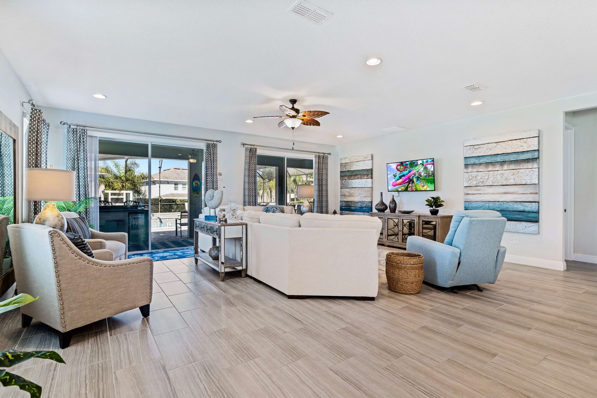 A spacious living area with a large sofa, a coffee table, and a TV mounted on the wall.