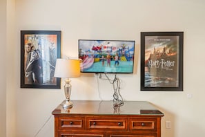 Ein Flachbildfernseher an der Wand, darüber drei gerahmte Poster.