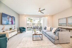 Ein Wohnzimmer mit Fernseher, Sofa, Couchtisch und einem Balkon mit Blick.