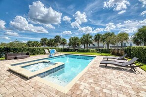 A rectangular pool with a hot tub, surrounded by lounge chairs and a brick patio. - Encore 8BR Villa, Home Theater, Near Disney (Kissimmee)