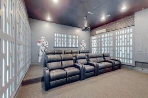 A home theater room with a reclining sofa, a ceiling projector, and Star Wars-themed wall decorations. - 9BR Reunion Mansion Pool, Spa & Home Theater (Kissimmee)
