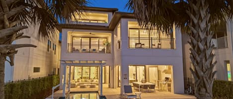 A modern two-story house with a pool, outdoor seating, and a balcony.