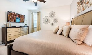 A bedroom with a bed, a dresser, a ceiling fan, wall art, and a television. - Delightful Home With Private Pool Oasis in Encore (Kissimmee)