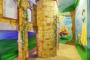 Ein Kinderspielbereich mit Burgmotiven an den Wänden und Wandgemälden von Zeichentrickfiguren.