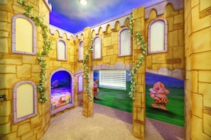 Ein kinderspielzimmer im Burgstil mit Bett, Bögen und Wandgemälde.