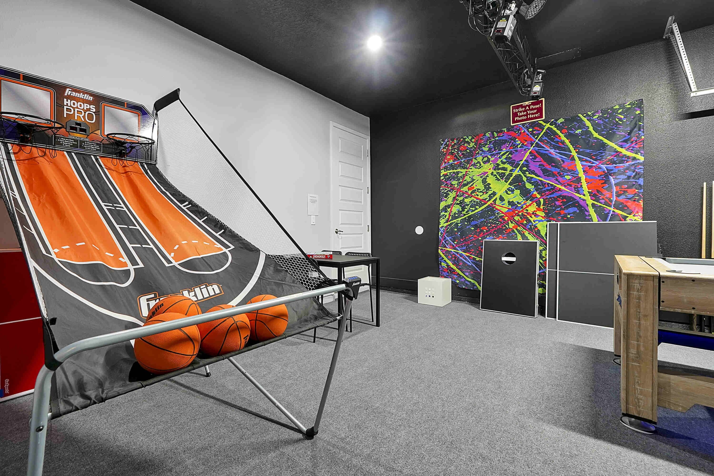 A basketball hoop with a net, a colorful abstract wall art, and a small table with a chair.